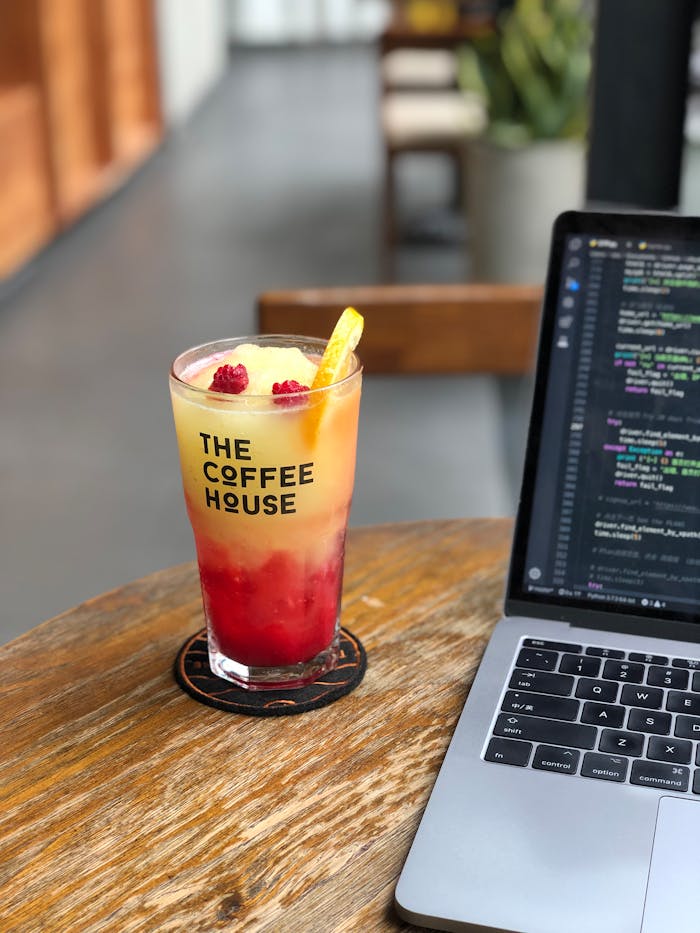 The Art of Drawing Readers In: Your attractive post title goes here Chilled raspberry lemonade and coding on a laptop at a modern coffee house.